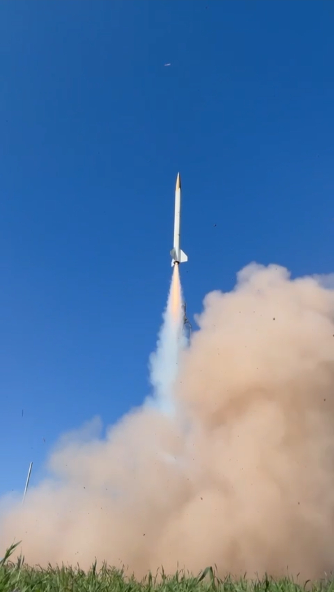 A solid rocket motor lifting off, with a large exhaust and dust cloud at the launch pad